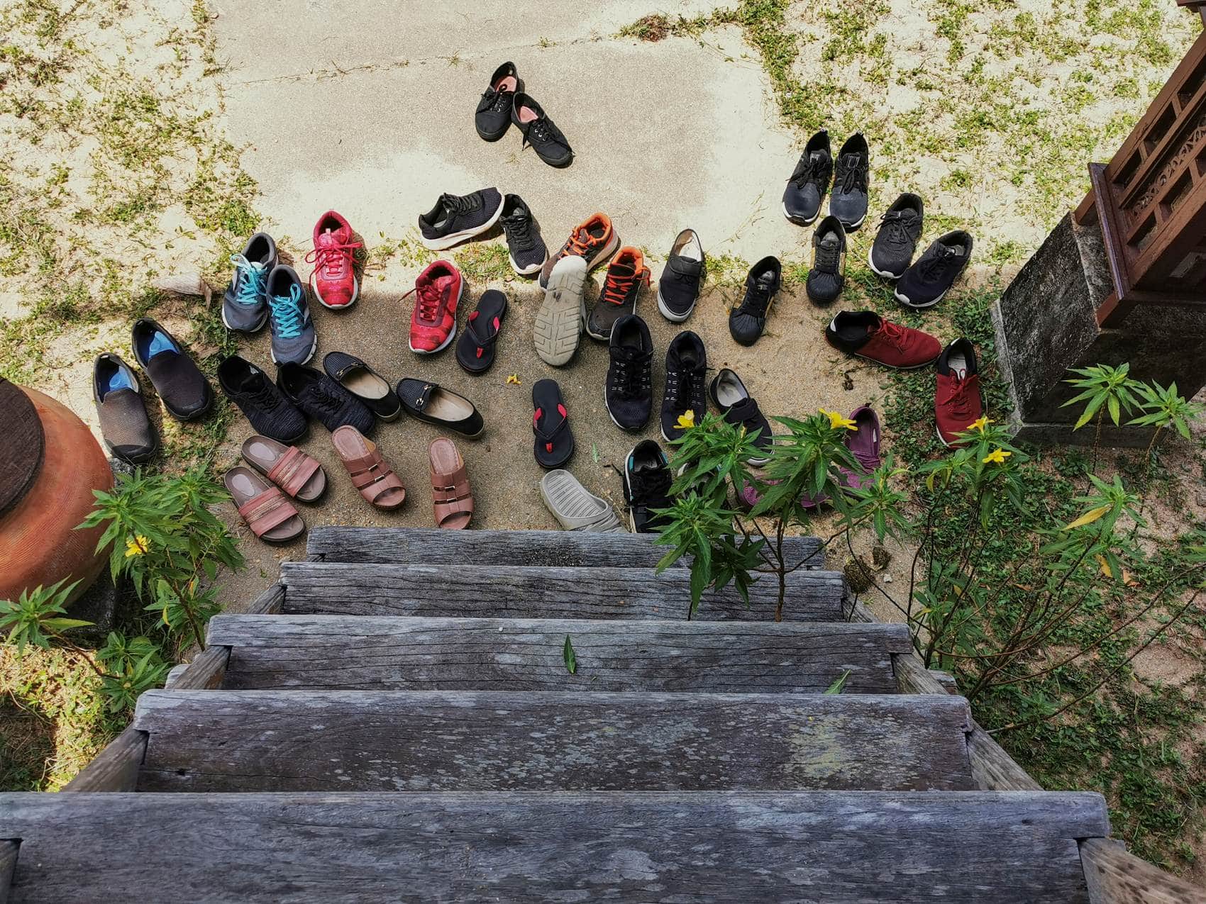 Mehr als ein Dutzend Paar Schuhe liegen auf dem Boden vor Hauseingang 