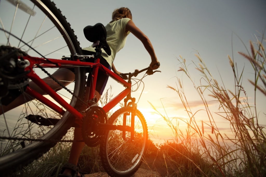 Frau schiebt Fahrrad in der Natur, Küste