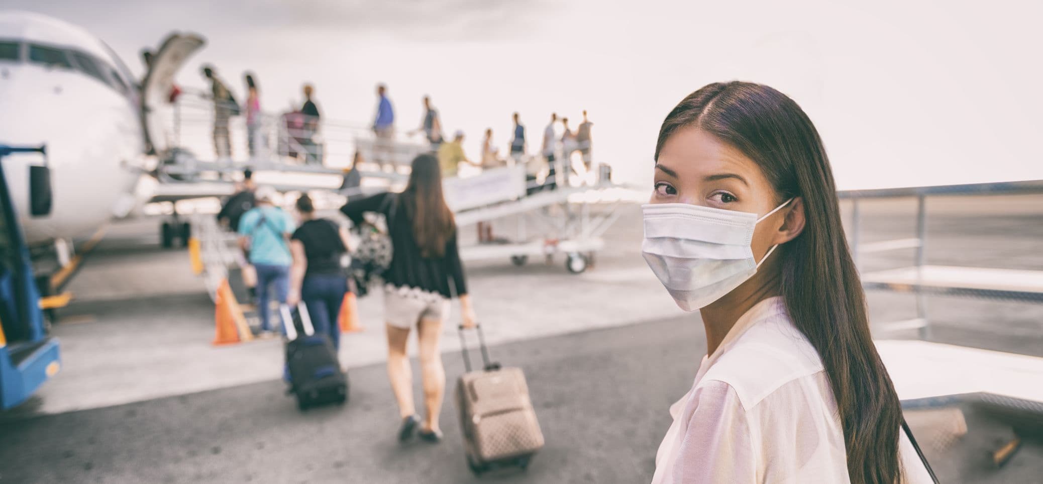 Reisende mit Mundschutz in Coronavirus-Zeiten