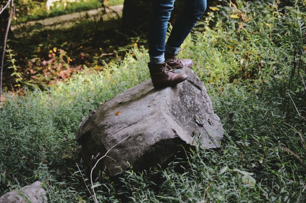 Wanderer steht in der Natur auf einem großen Stein