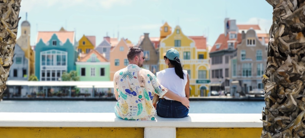 Paar sitzt in Willemstad am Ufer und blickt auf die Handelskade