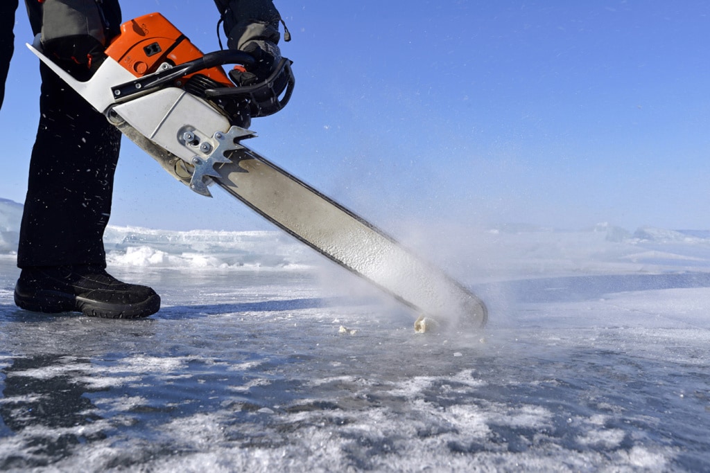 Mit einer Kettensäge wird ein Loch in die Eisdecke des Baikalsees gefräst, damit die Taucher einsteigen können.