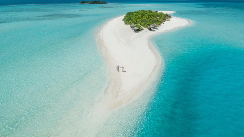 Pärchen spaziert über kleine Privatinsel in den Malediven. Dort versprechen die Resorts Luxus pur.