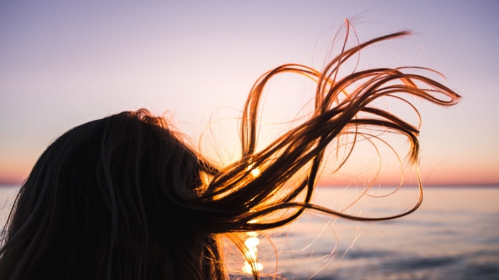 Haare einer Frau am Meer wehen im Wind