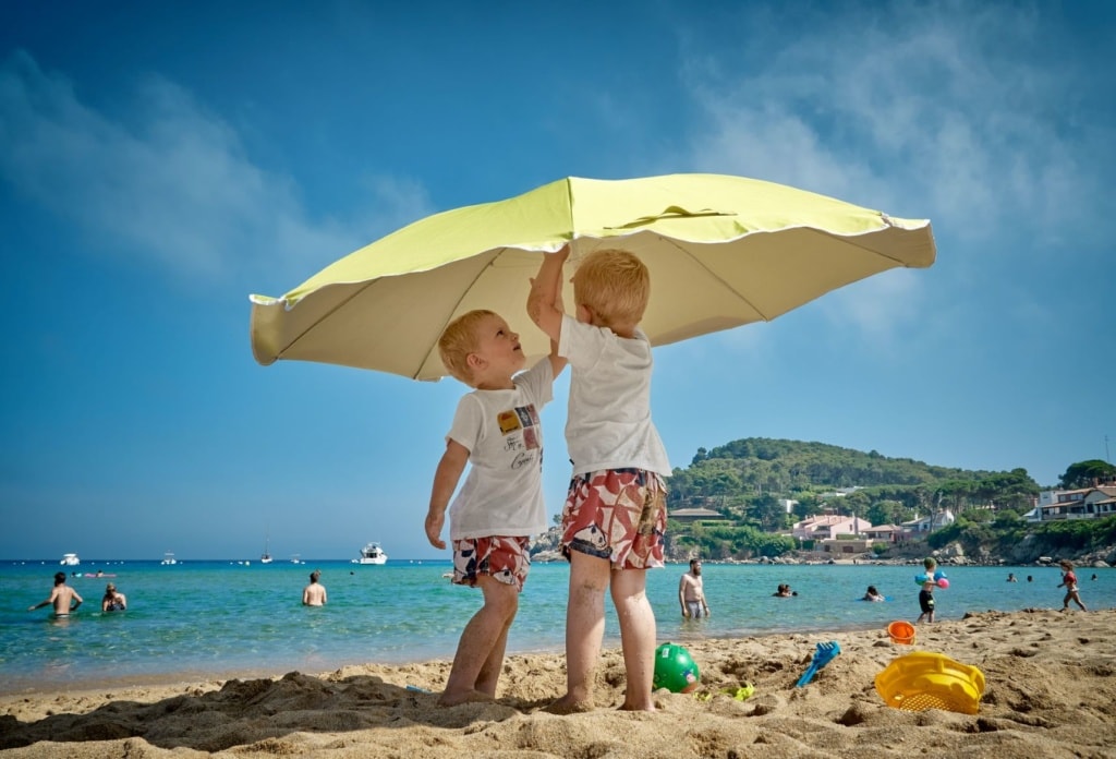 Zwei kleine Jungen mit Sonnenschirm am Strand