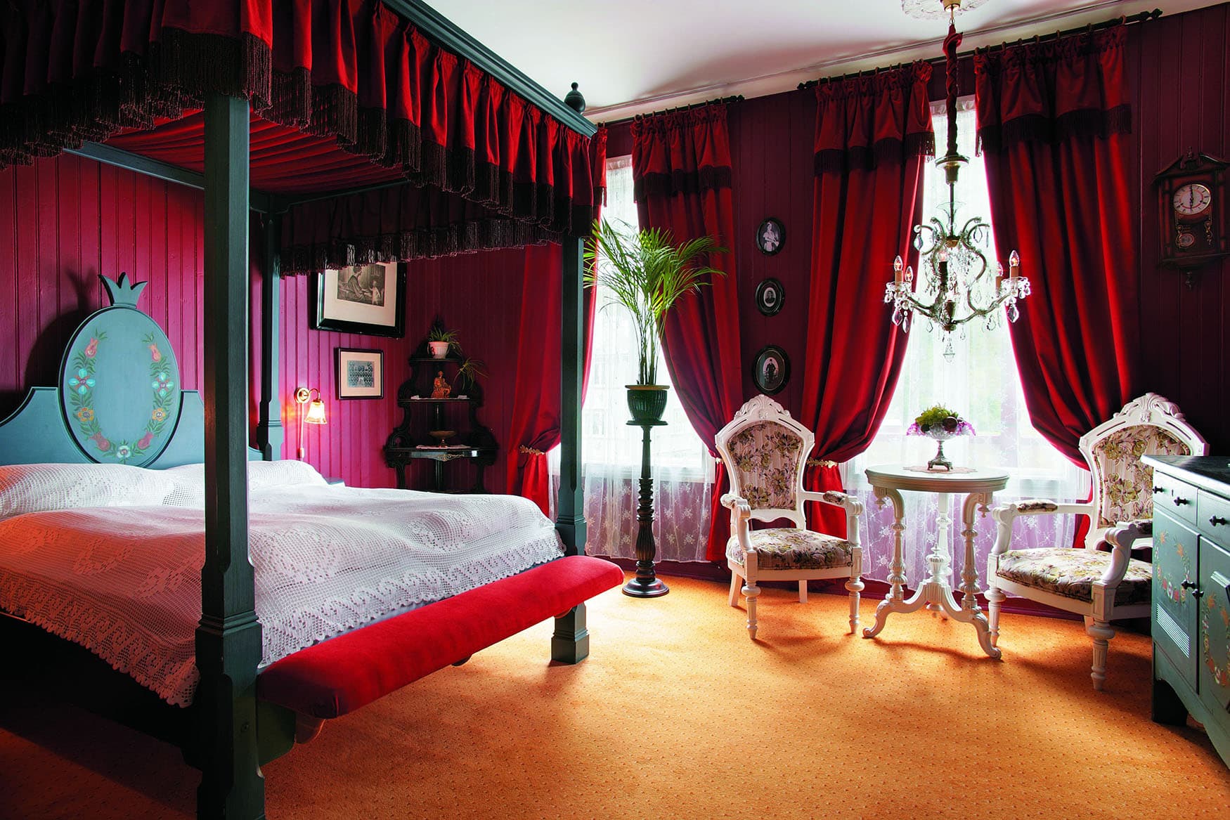 Ein Hotelzimmer mit roten Samtvorhängen, Himmelbett und Antiquitäten