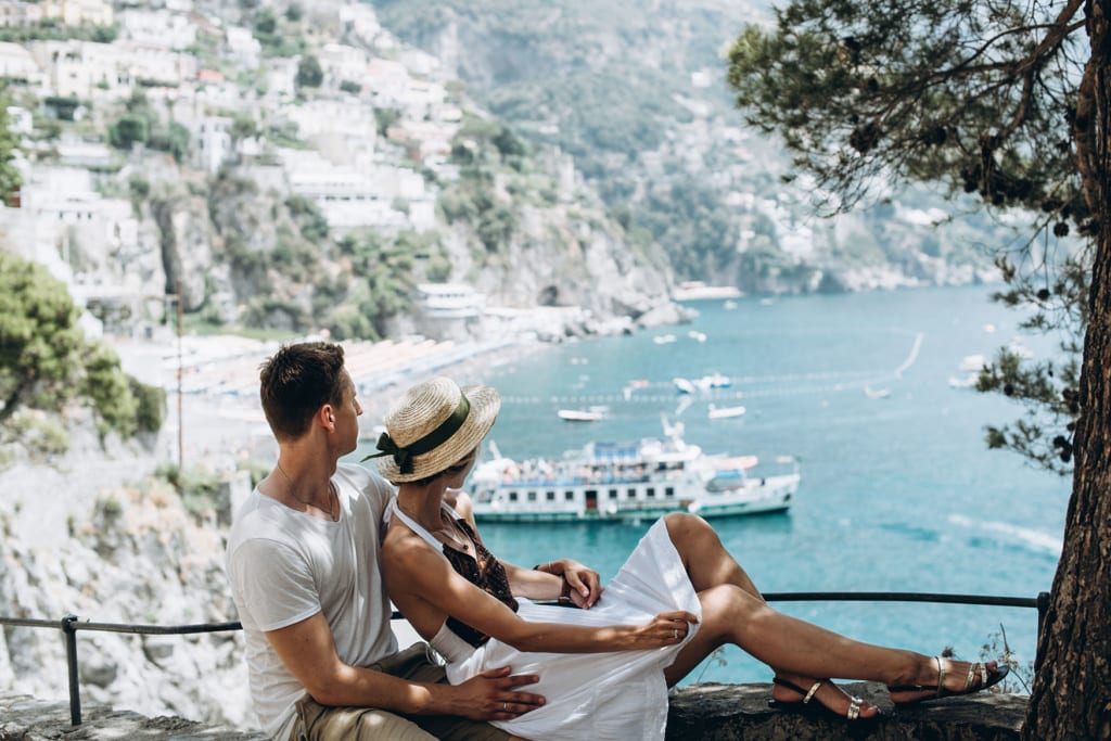 Paar sitzt auf einer Mauer mit Blick auf Positano