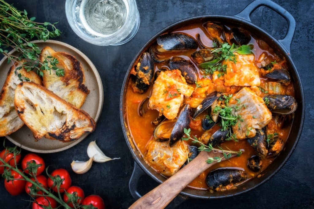Traditioneller französischer Fischeintopf mit Muscheln und Knoblauchbaguette