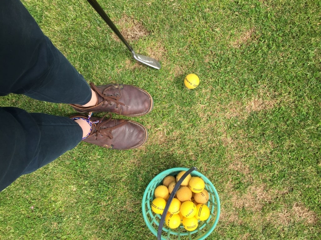 Eimer mit Golfbällen steht auf Wiese