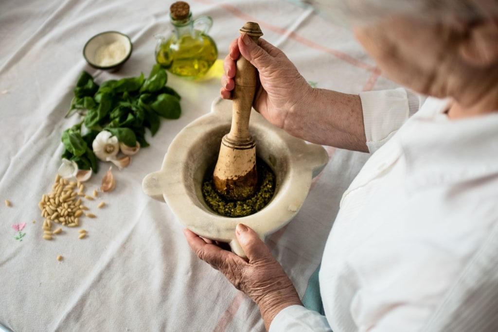 Eine dame bereitet ein grünes Pesto in einem Mörser zu