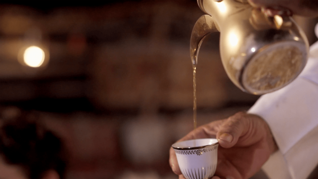 Mann schenkt arabischen Kaffee aus einer Dallah ein