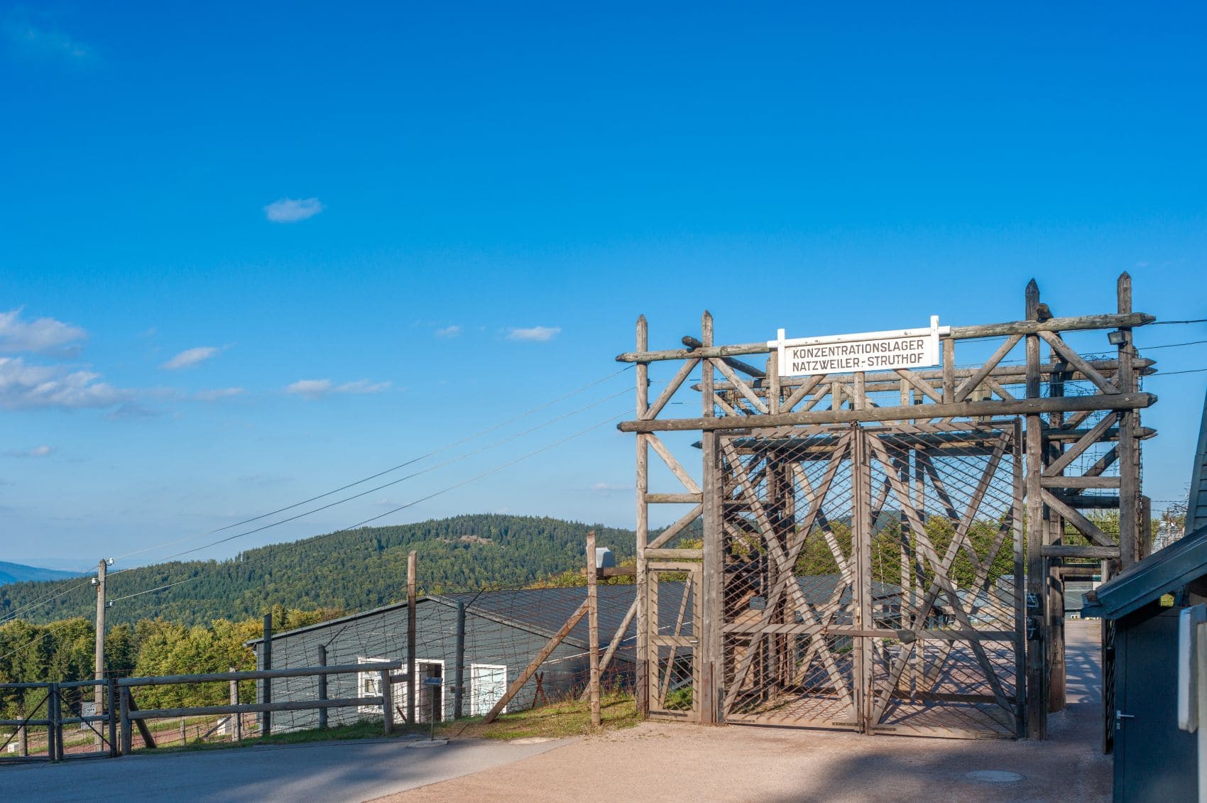Eingang des Konzentrationslagers Natzweiler-Struthof im Elsass, Frankreich; Ein hölzernes Doppeltor, mit Draht verstärkt, darüber ein Schild