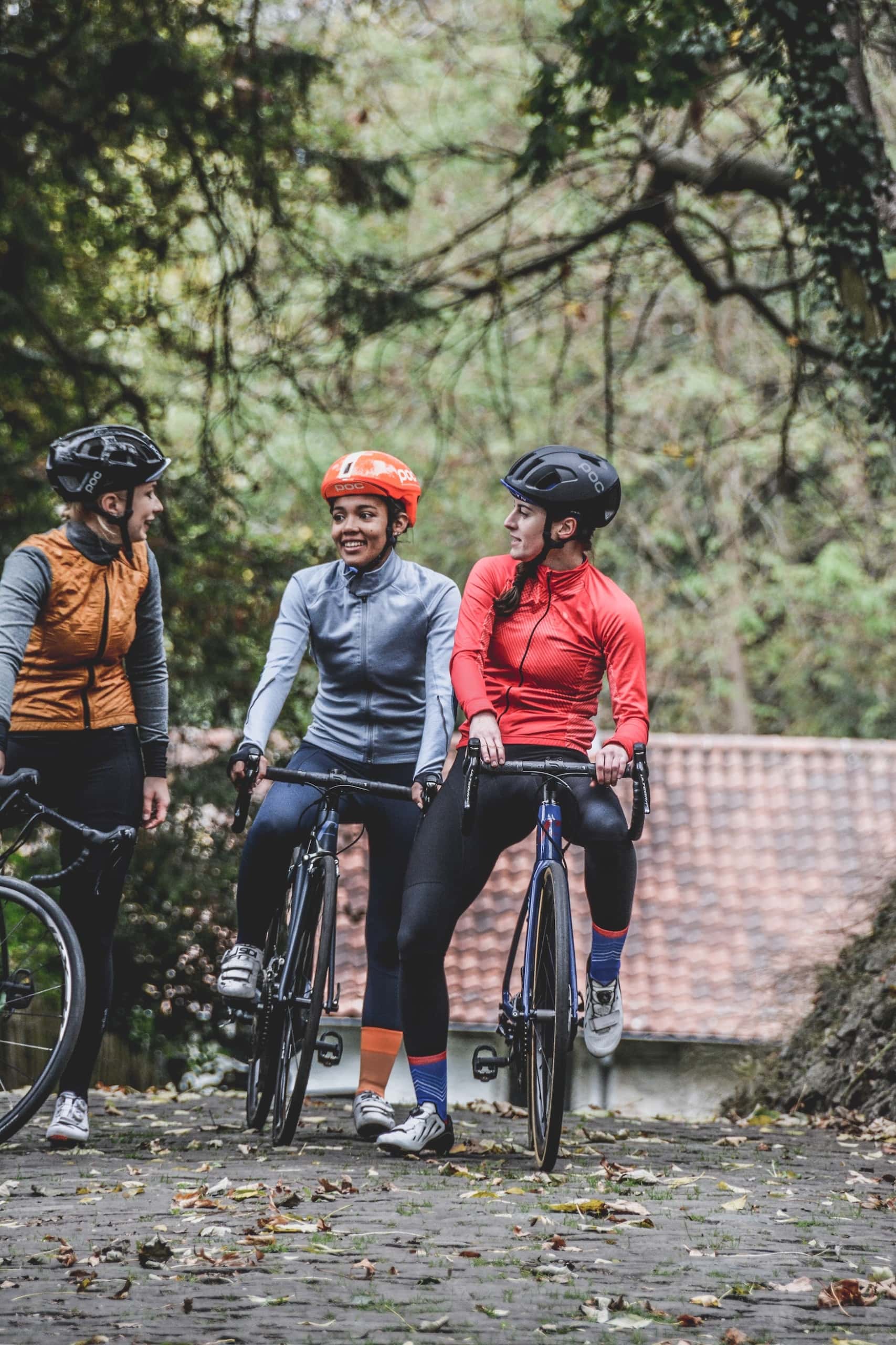 Drei Frauen mit Rennrädern tragen Helm für sicheres Fahrradfahren im Straßenverkehr