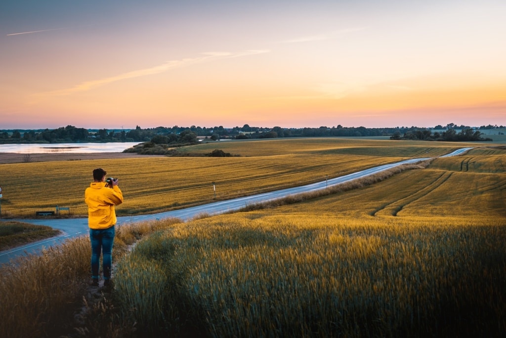 Mann mit gelber Jacke fotografiert Landschaft in Roskilde