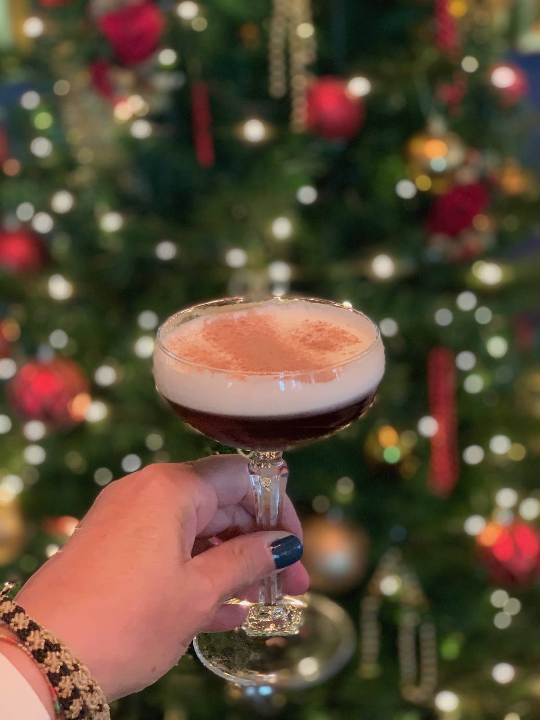 Autorin Simone Sever hält Espresso Martini vor Weihnachtsbaum im The Grand Brighton