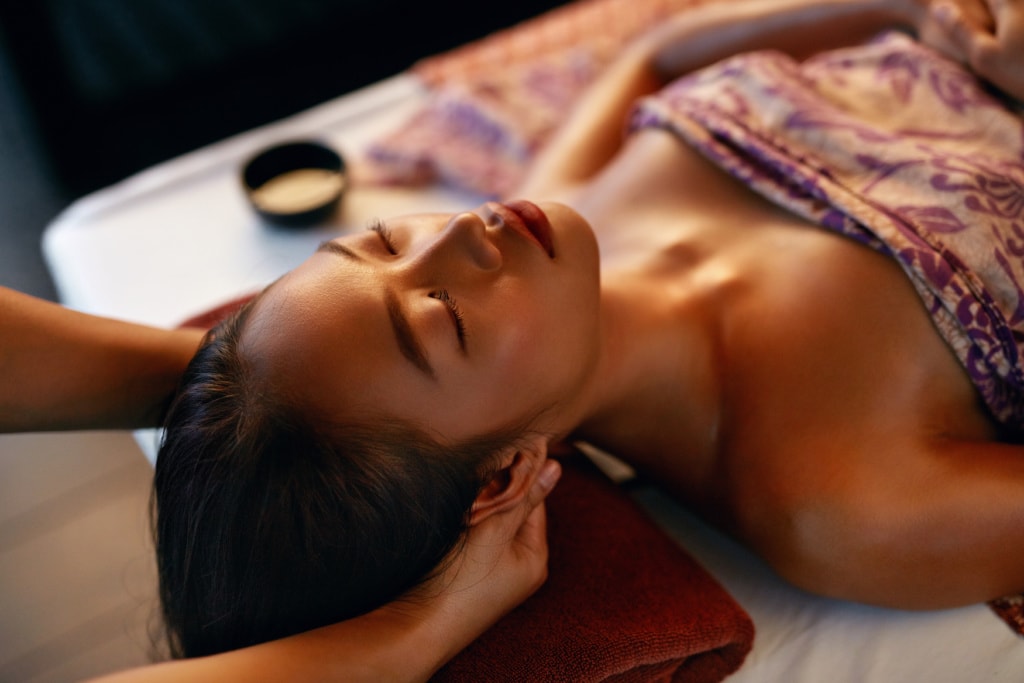 Asiatische Frau wird am Kopf massiert während einer Thai-Massage