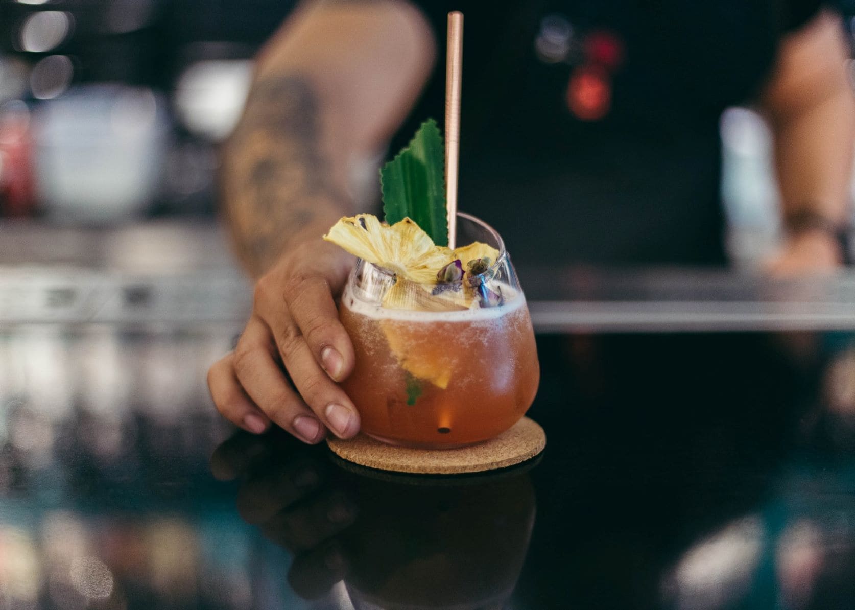 Hand stellt Cocktail auf Tisch