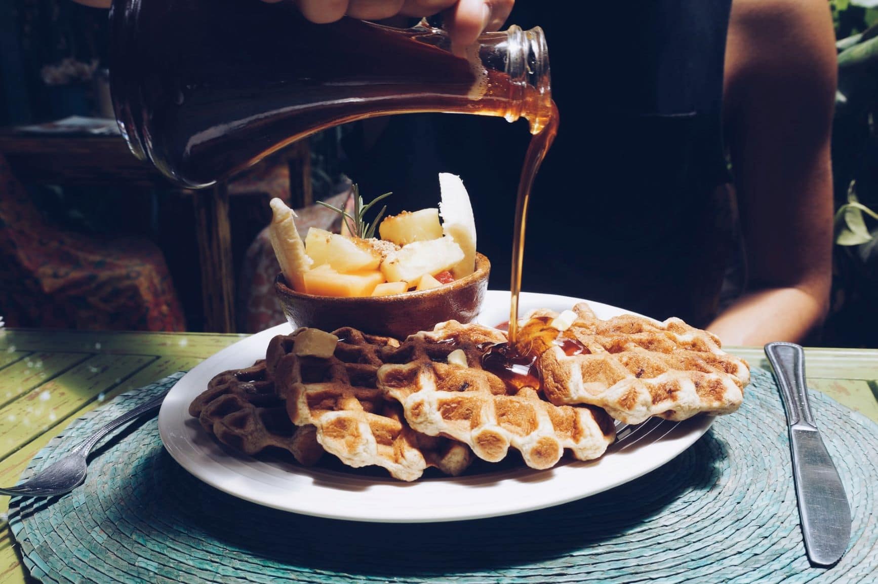 Frau schüttet Sirup über Waffeln
