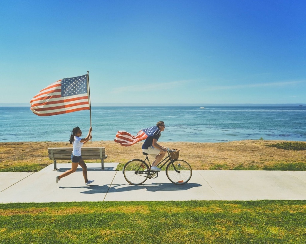 Junge und Mädchen mit USA-Flaggen am Meer