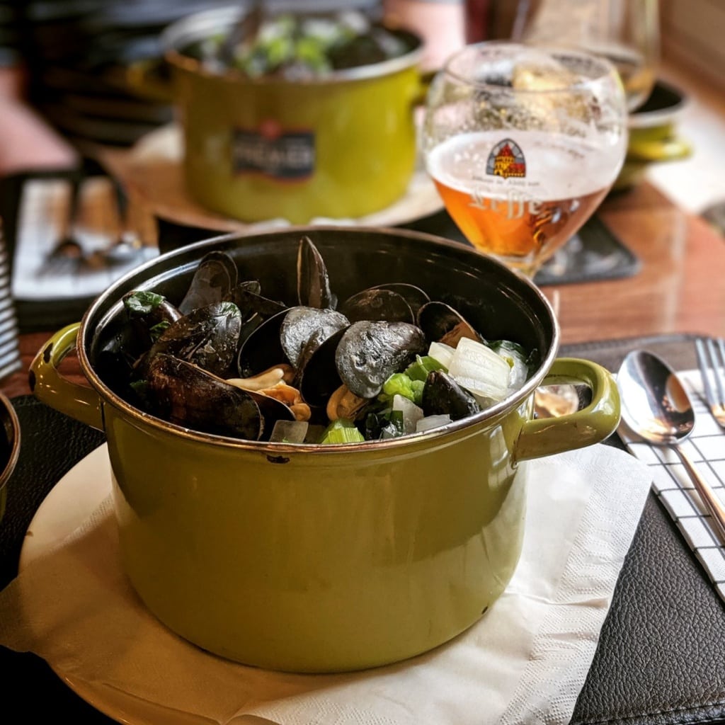 Topf gefüllt mit Muscheln, Glas Bier 