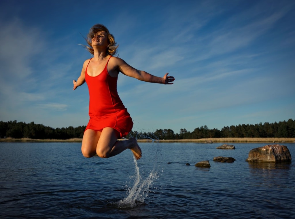 Frau macht Sprung in einem See in Finnland