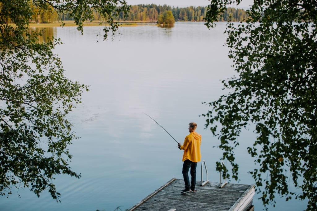 Junger Mann angelt in einem See in Finnland