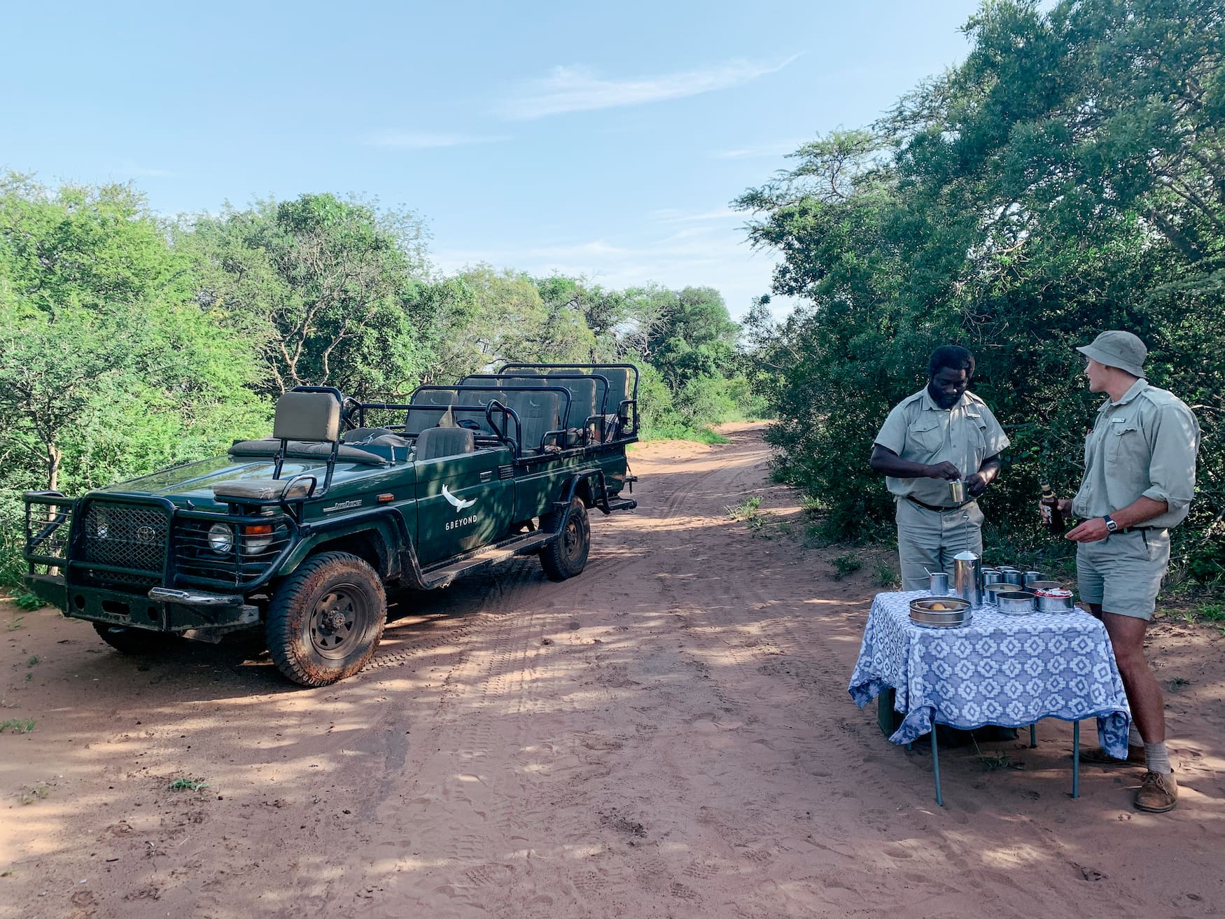 Zwei Ranger stehen an aufgebauter Bar im Busch in Südafrika
