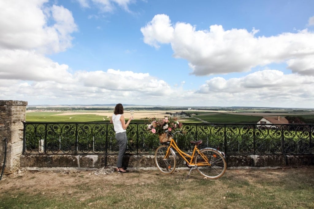 Frau mit Fahrrad trinkt Glas Champagner in der Champagne