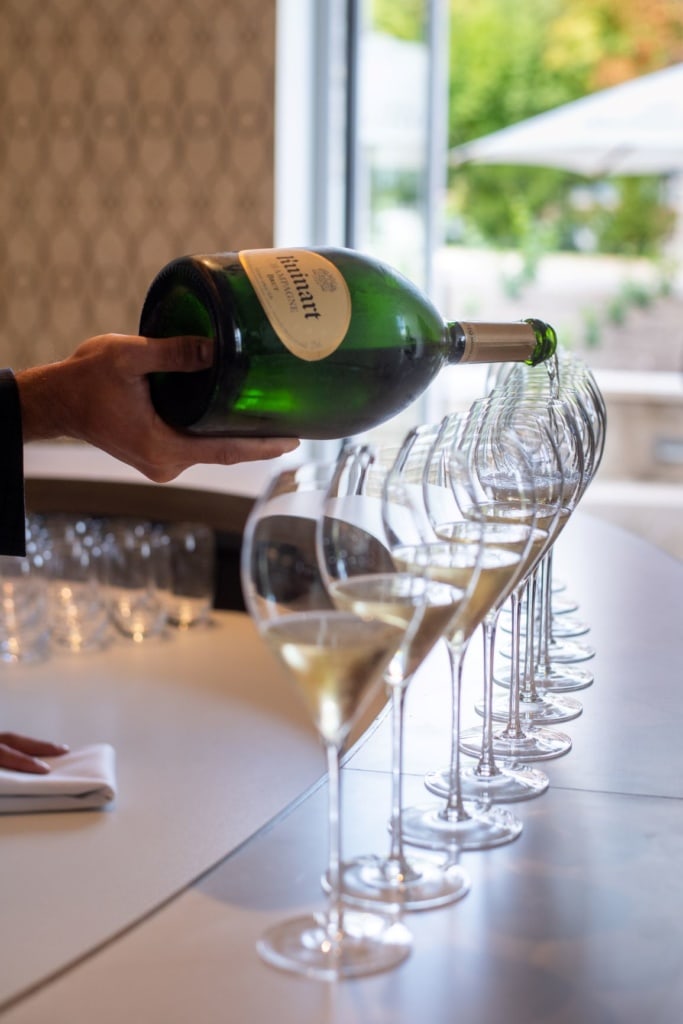 Jemand schüttet Ruinart-Champagne in Gläser
