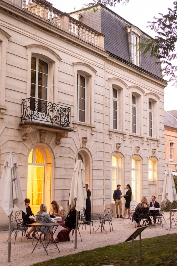 Auf einer Terrasse eines Landhauses in der Champagne sitzen und stehen Gäste