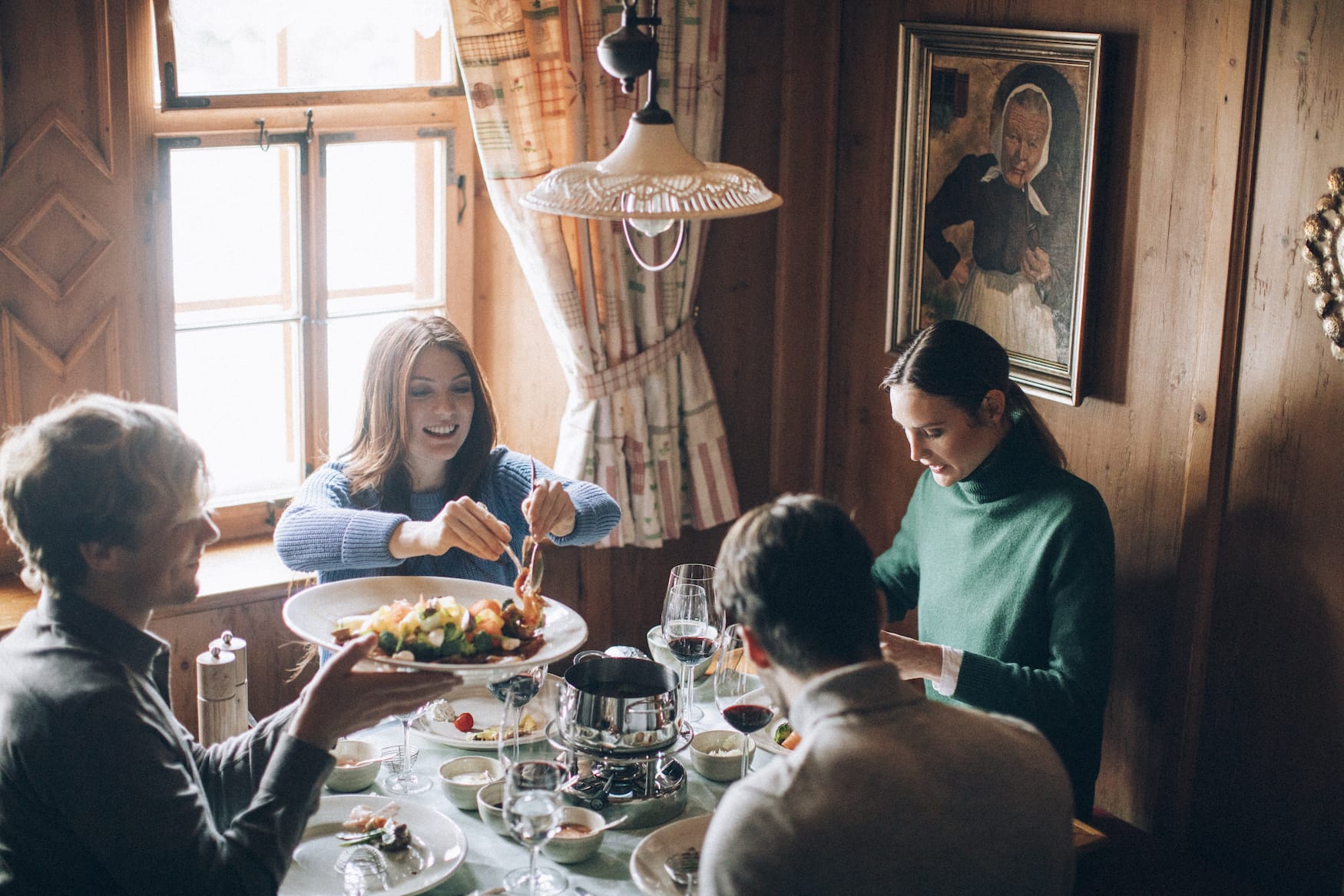Vier Freunde sitzen bei geselligem Fondue-Abend im Hotel Arlberg