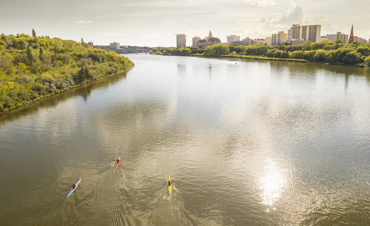 Kanufahrer auf einem Fluss mit der Skyline von Saskatoon im Hintergrund