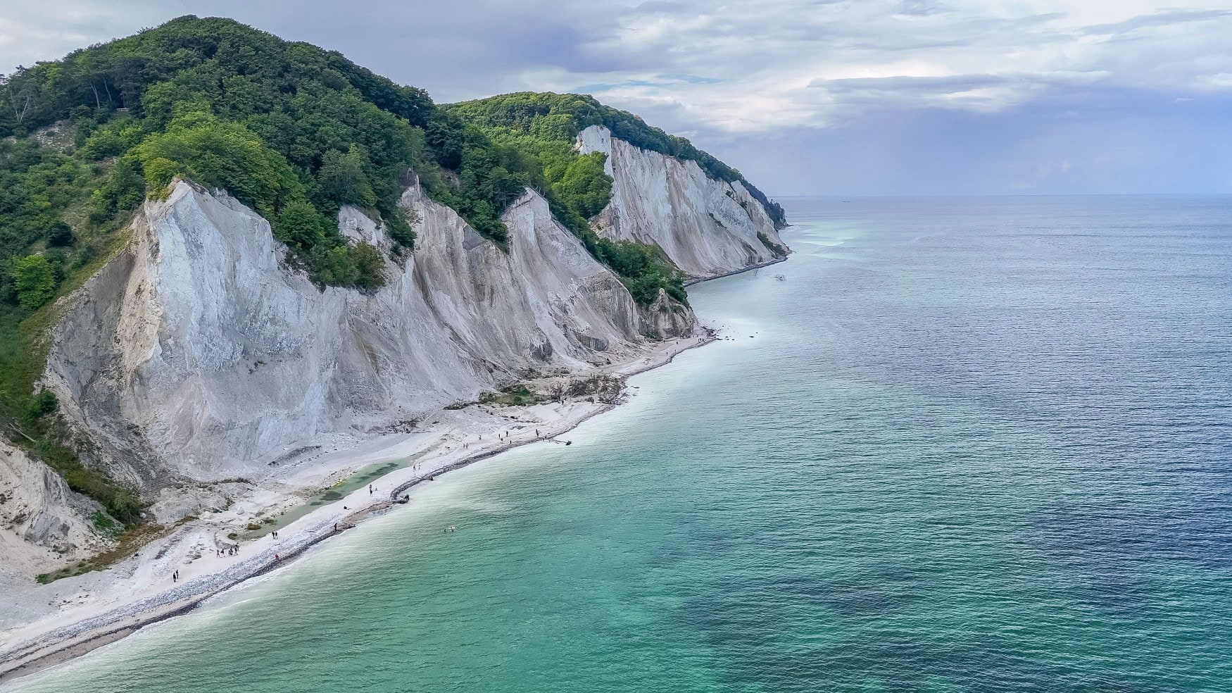 Drohnenaufnahme der weißen Kalkklippen von Mons Klint in der Nähe von Kopenhagen; links die Klippen, rechts das blaue Meer.