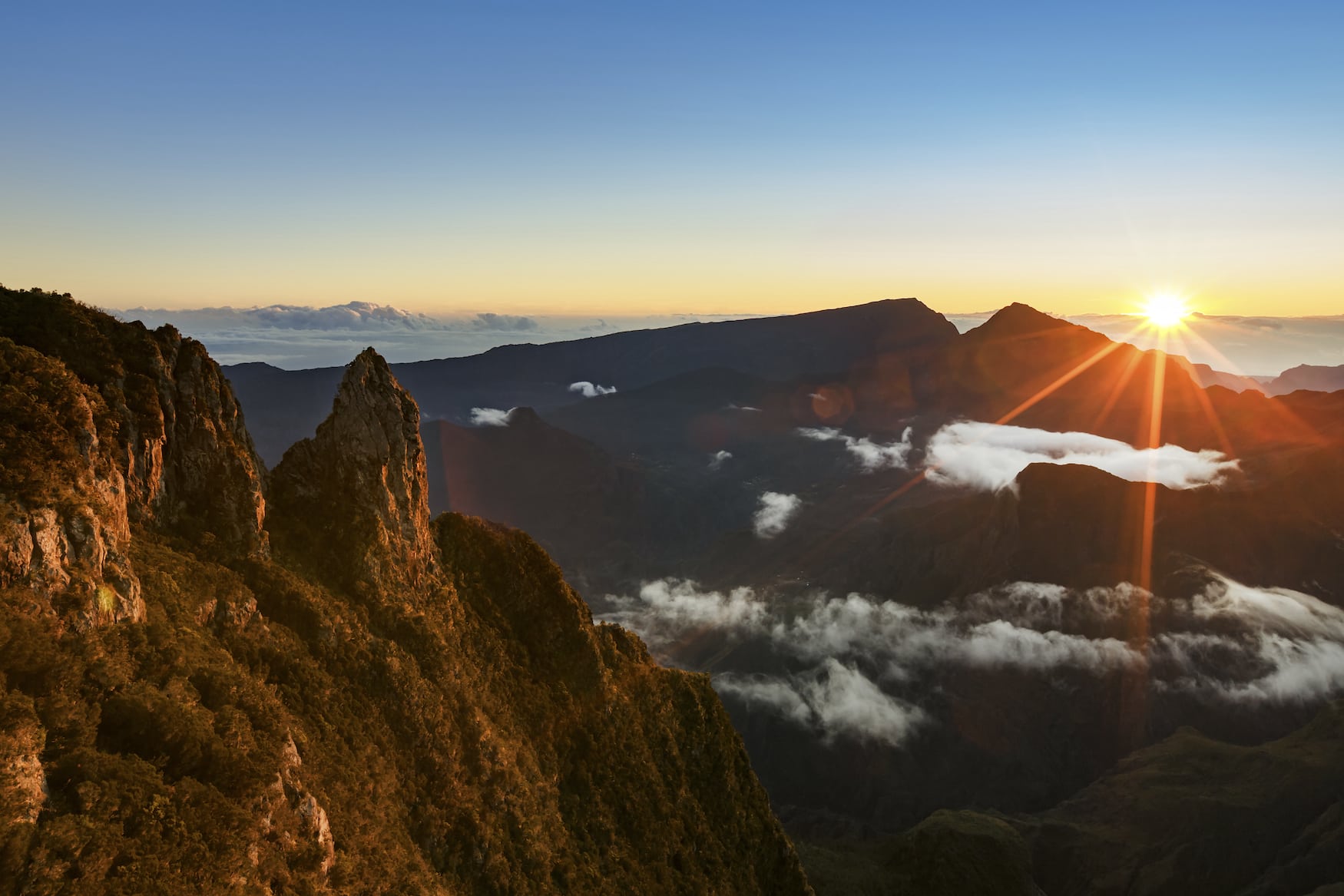 Sonnenaufgang über einem Gebirge auf La Réunion, wo es sich prima wandern lässt