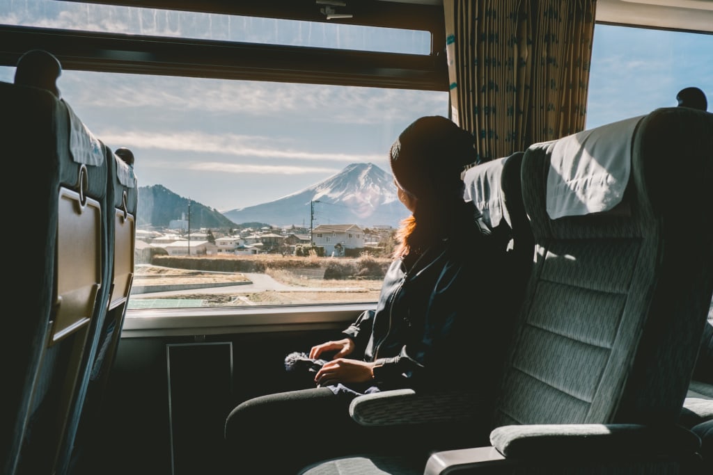 Junge Frau guckt aus dem Fenster während Zugfahrt in Japan
