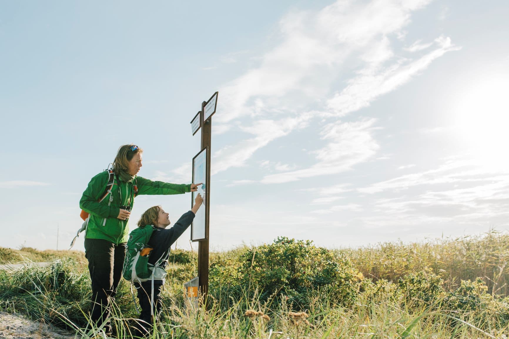 Frau und Kind vor Wander-Hinweistafel in Skaneleden, Schweden