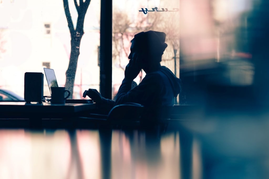 Mann sitzt im Kaffee vor Notebook