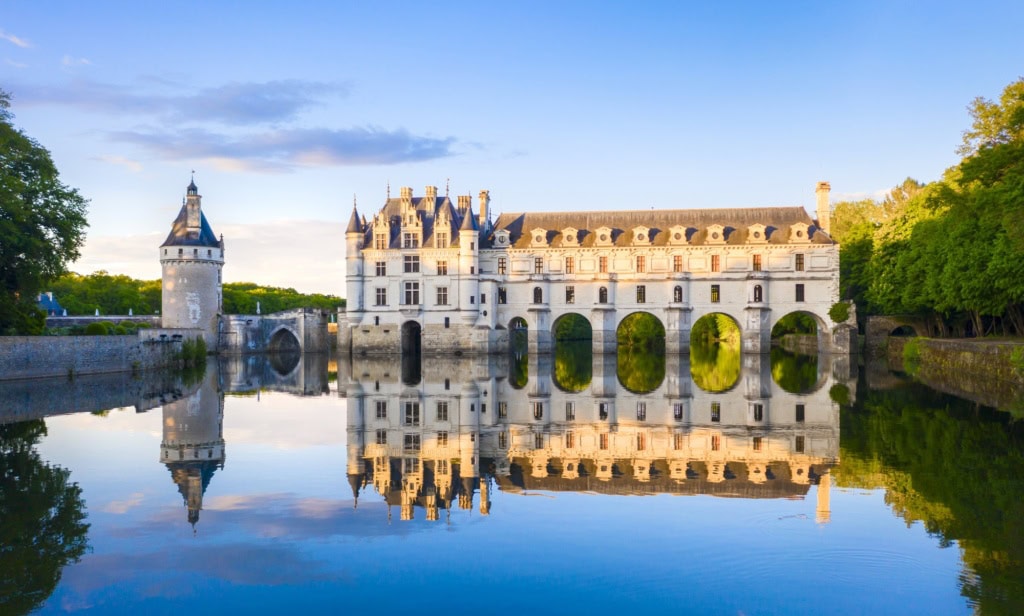 Blick auf das Chateau de Chenonceau im Loiretal, vom Schlossteich aus, in dem sich das Schloss im Licht der Abendsonne spiegelt.