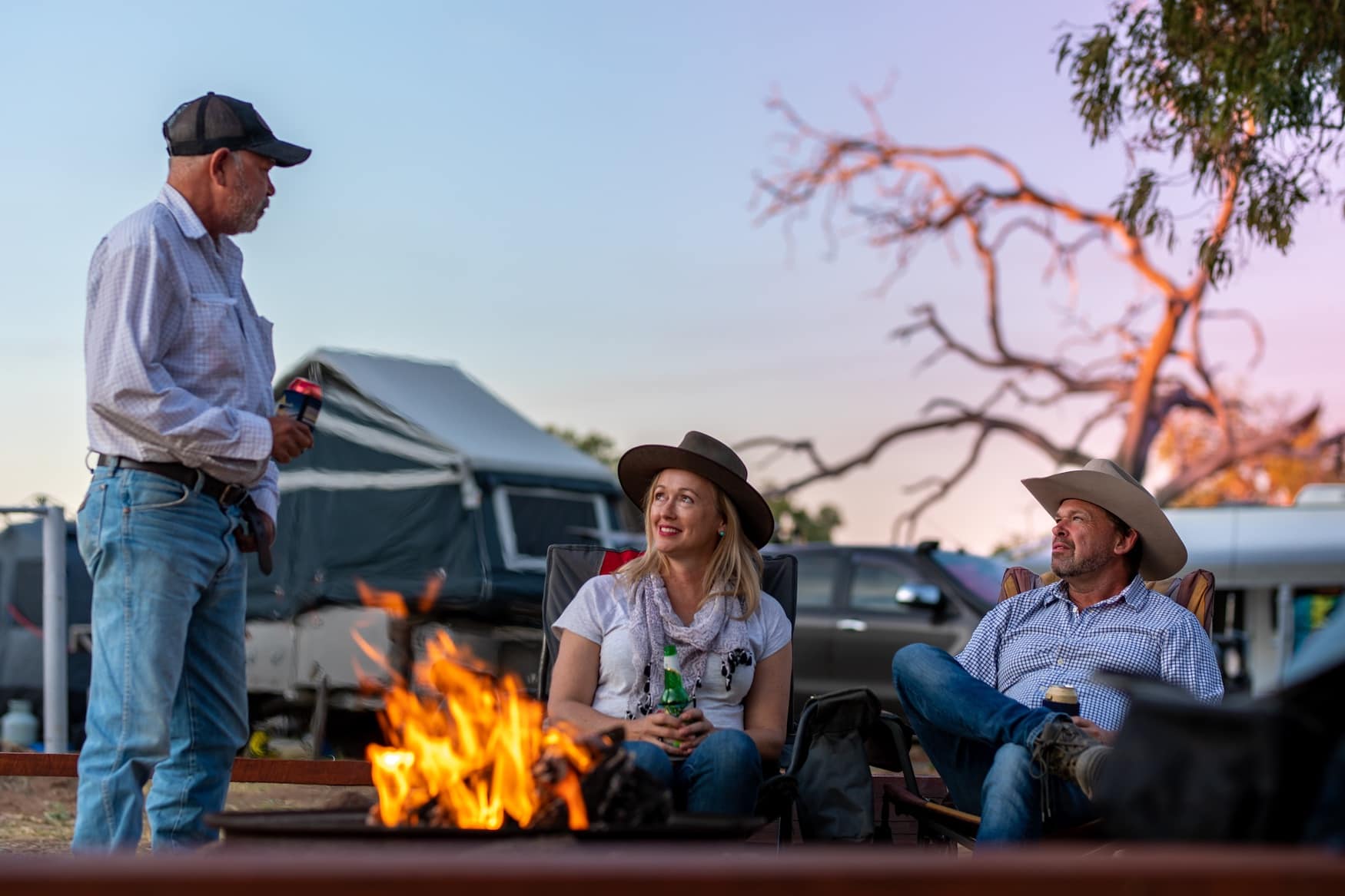 Menschen sitzen bei Lagerfeuer im Talaroo Camping am Abend