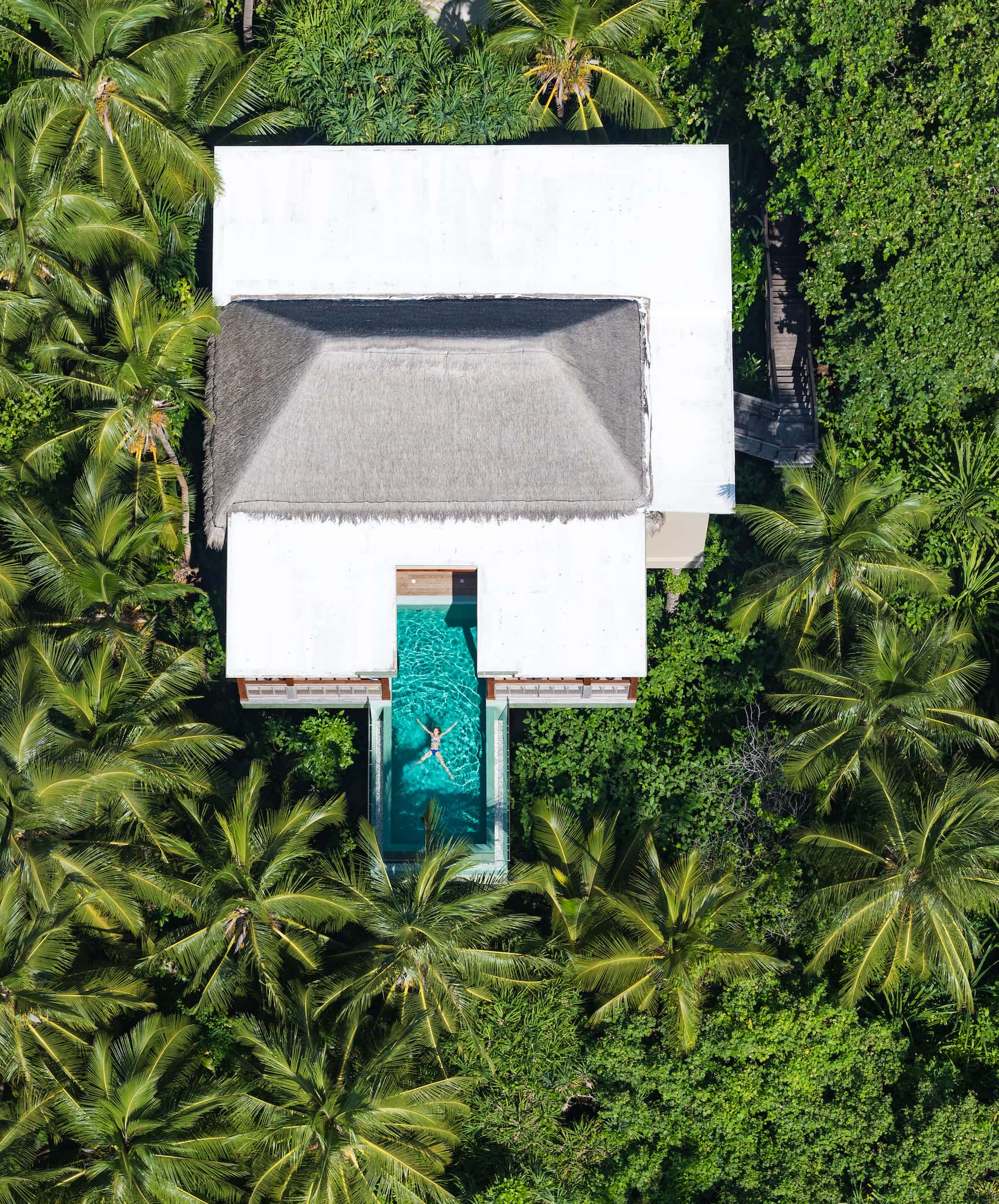 Frau schwimmt in Pool in der Tree House Villa des Amilla Fushi