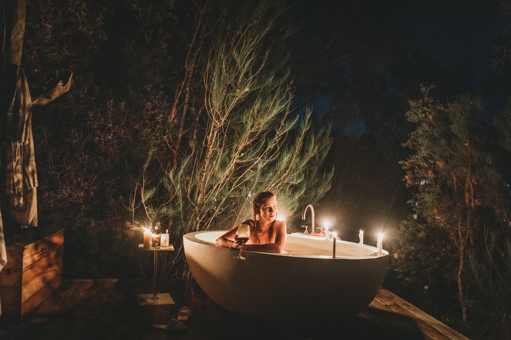 Frau sitzt mit Glas Wein in einer Outdoor-Badewanne im Pumphouse Point, Tasmanien