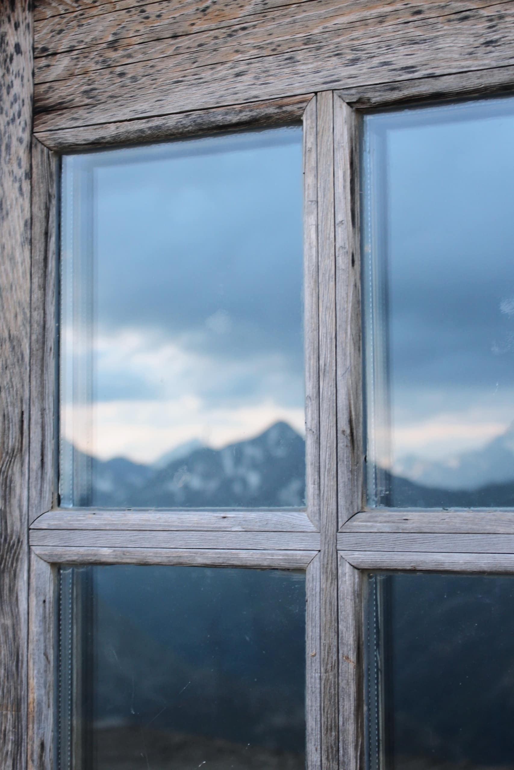 Die italienischen Alpen spiegeln sich in den Fenstern einer Berghütte bei Livigno.