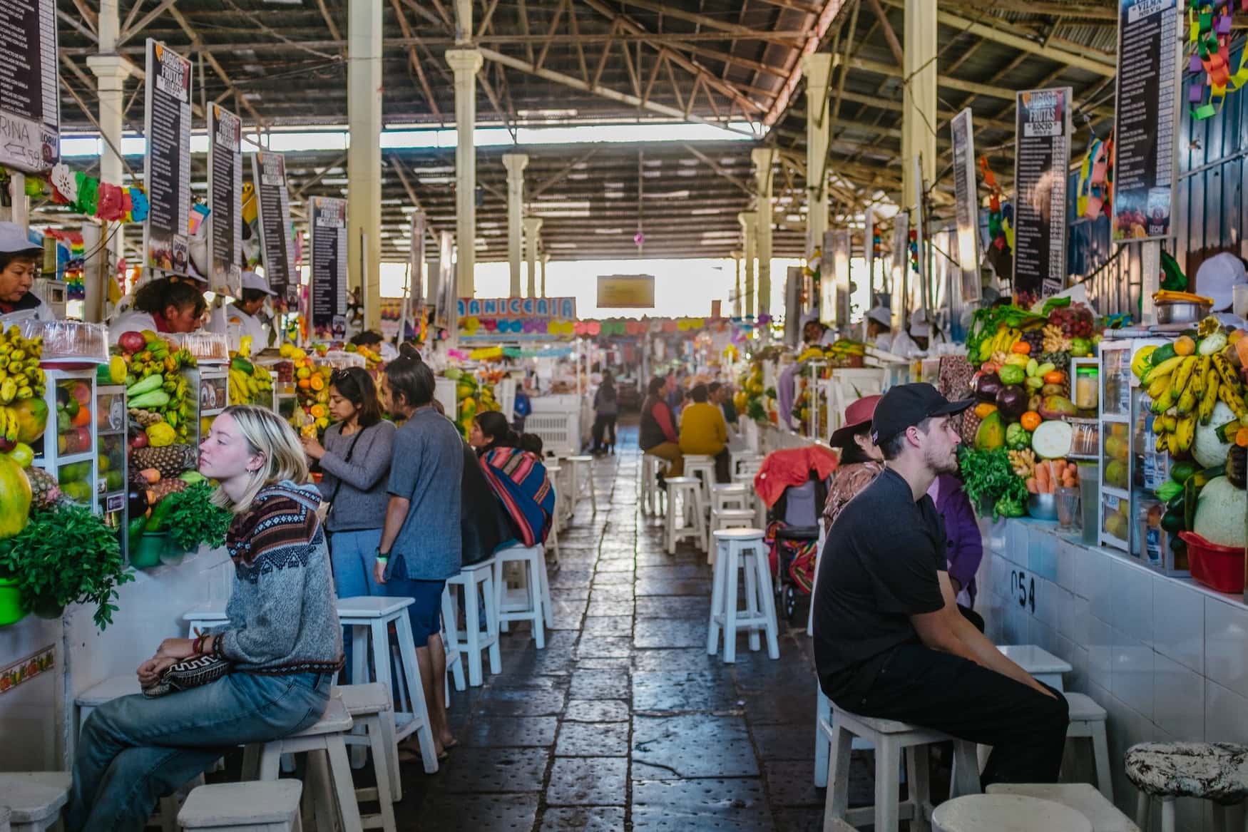 Junge Menschen sitzen im Mercado San Pedro in der peruanischen Stadt Cuzco