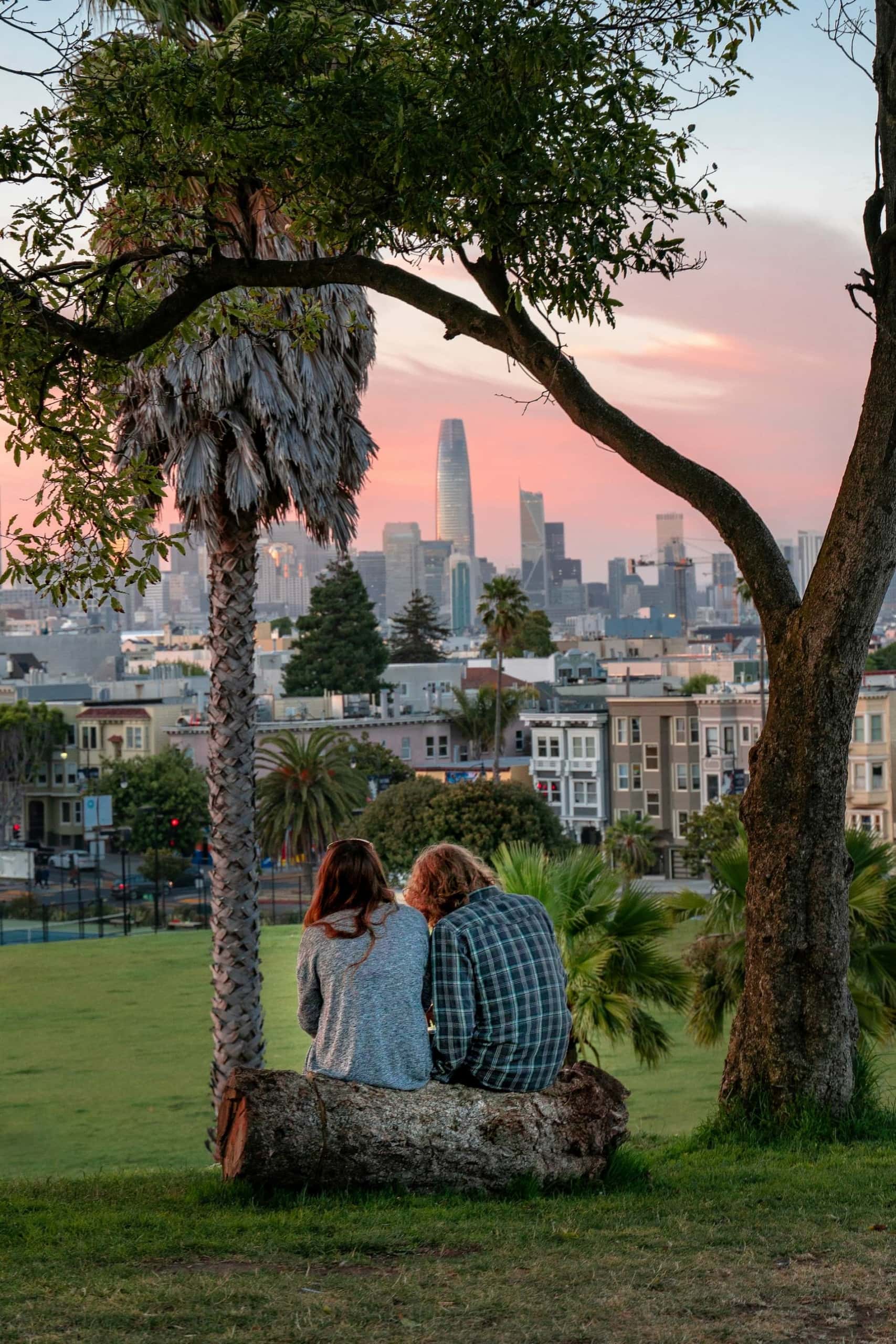 Mann und Frau sitzen auf Baumstamm im Dolores Park, San Francisco