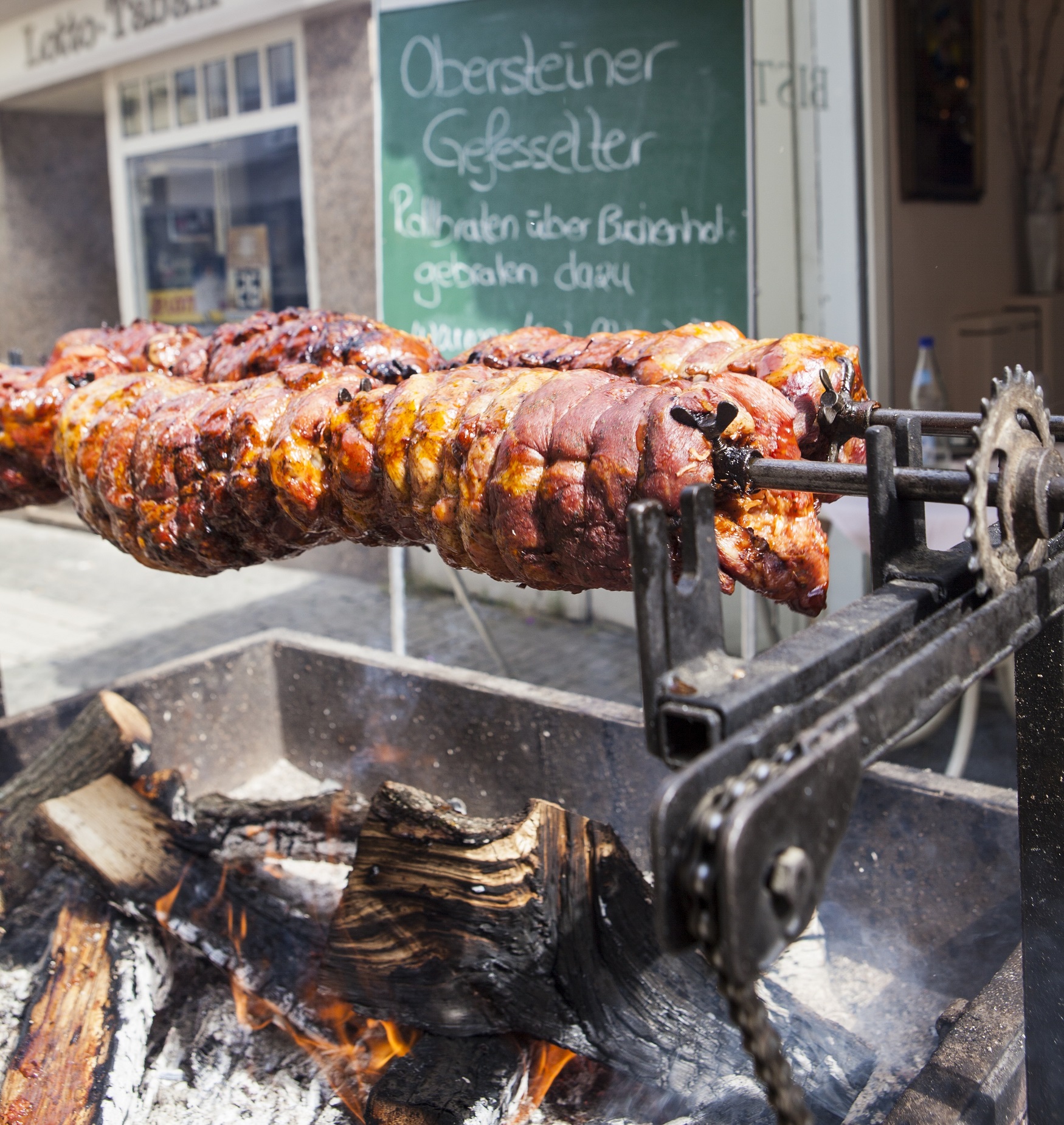Zwei Spießbraten sind aufgespießt und werden über einem Feuer gebraten