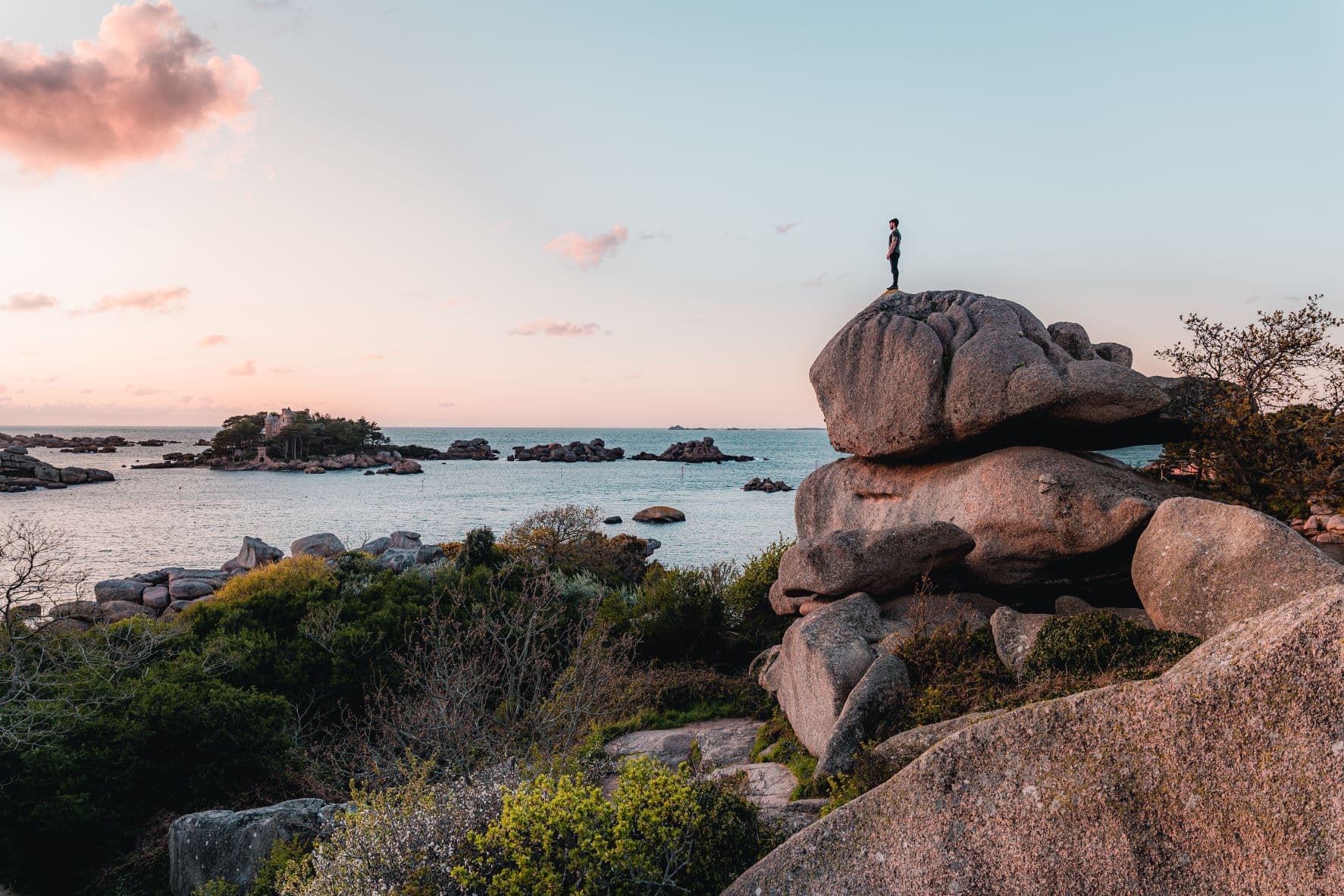 Mann steht auf Fels und blickt auf Meer am Cap Frehel in der Bretagne