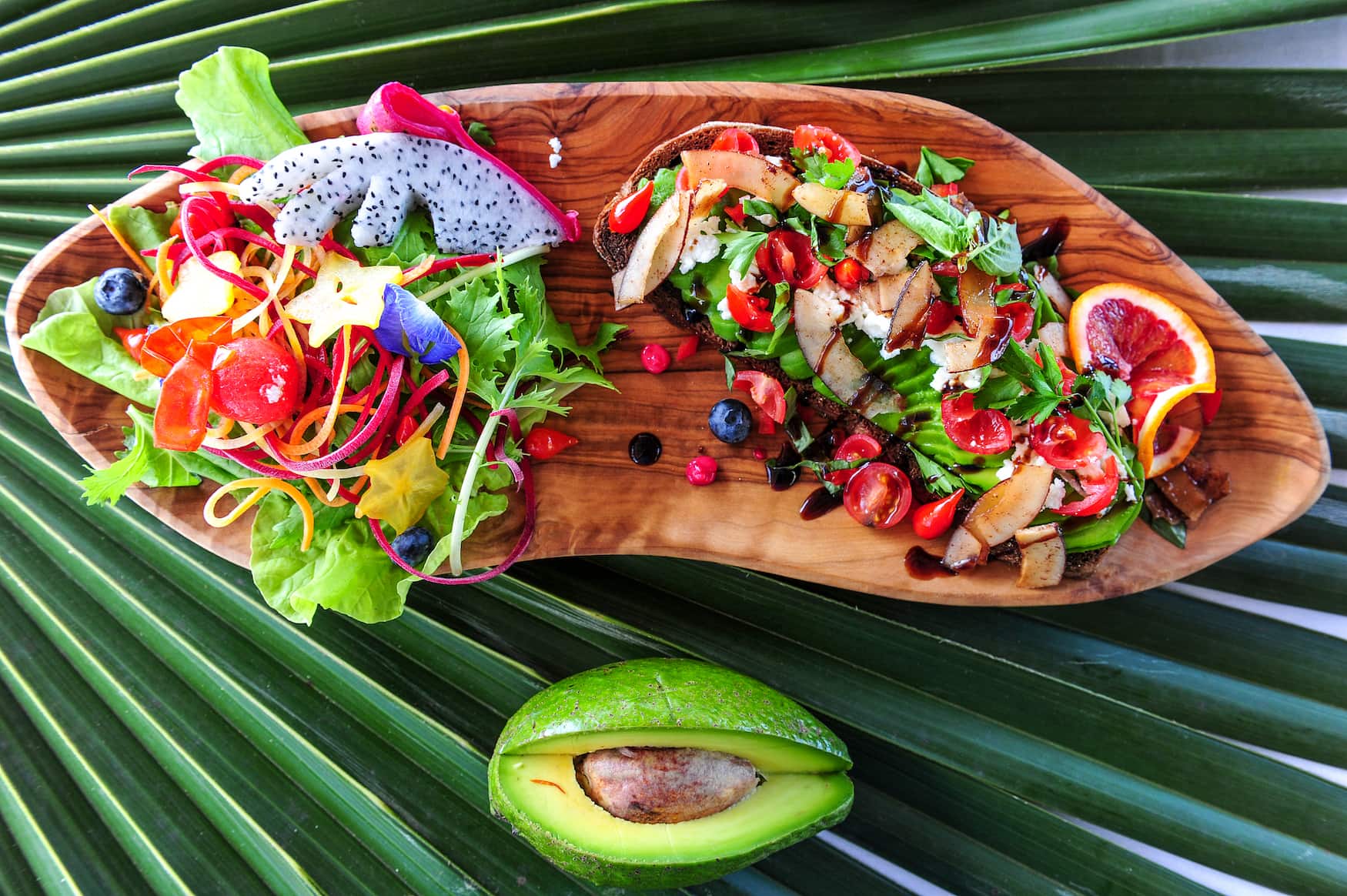 Buntes Avocado-Toast mit tropischen Früchten serviert in einem Café