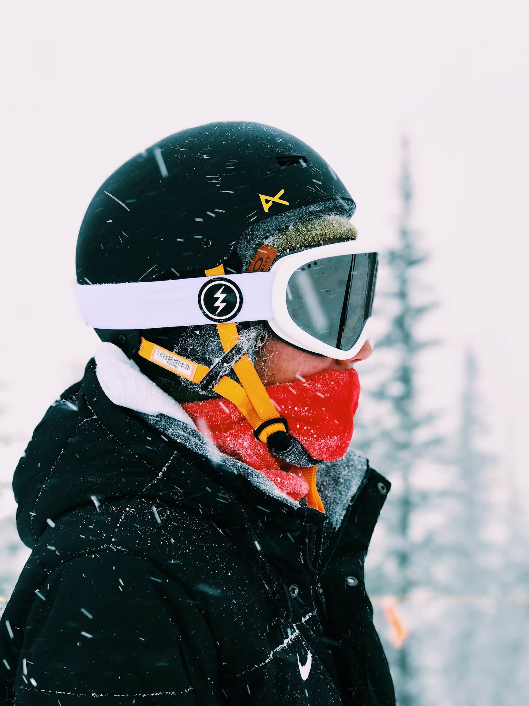 Frau steht in verschneiter Landschaft und trägt Skiausrüstung und Skihelm