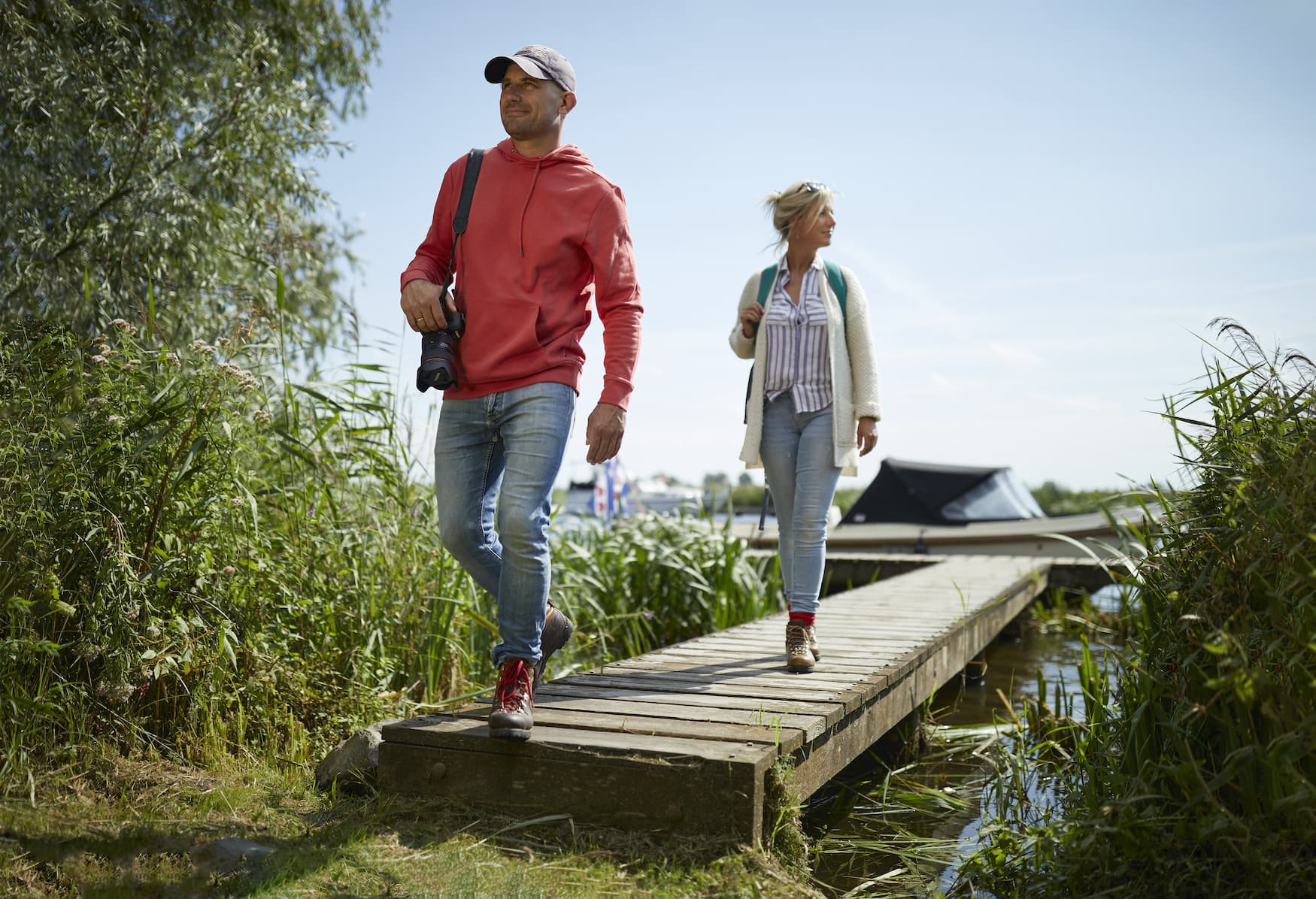Mann und Frau haben ihr E-Boot angelegt und spazieren über Steg