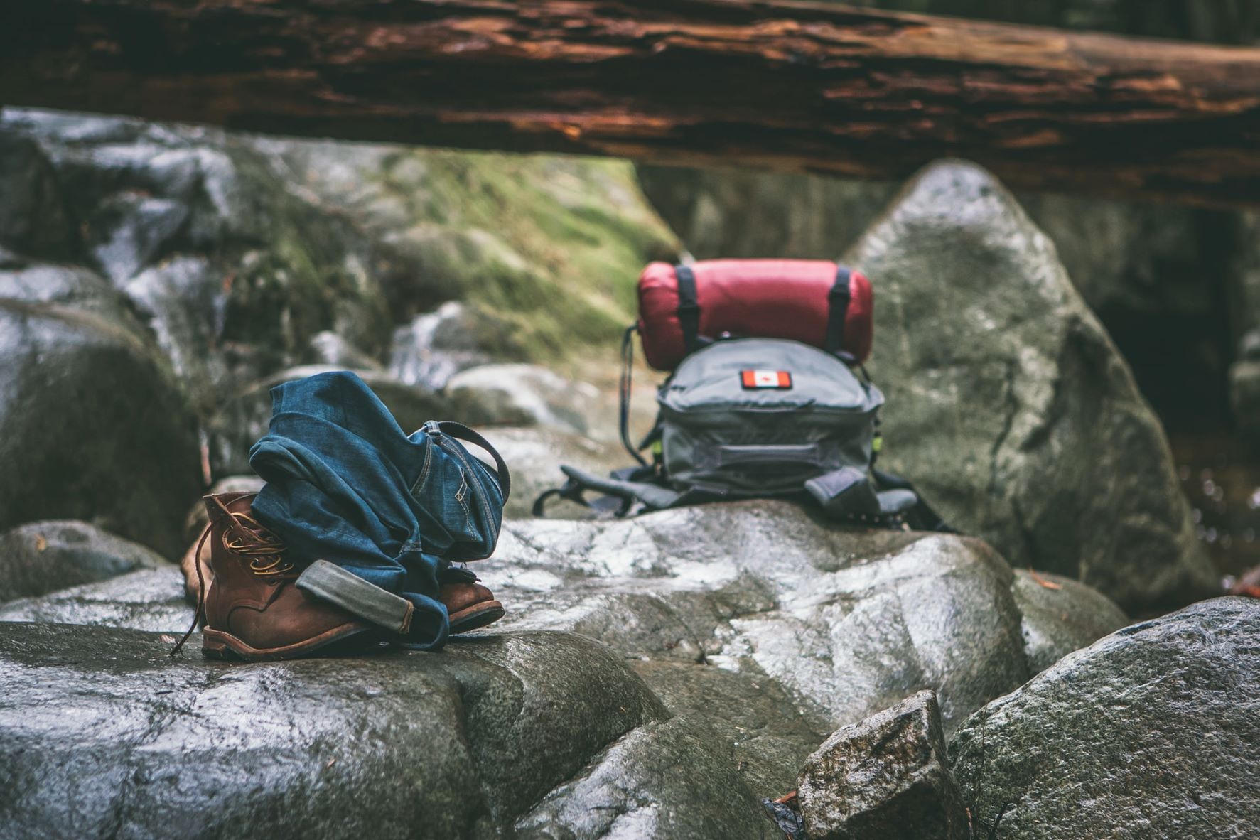 Rucksack, Hose und Schuhe liegen auf einen Steinen in der Natur 